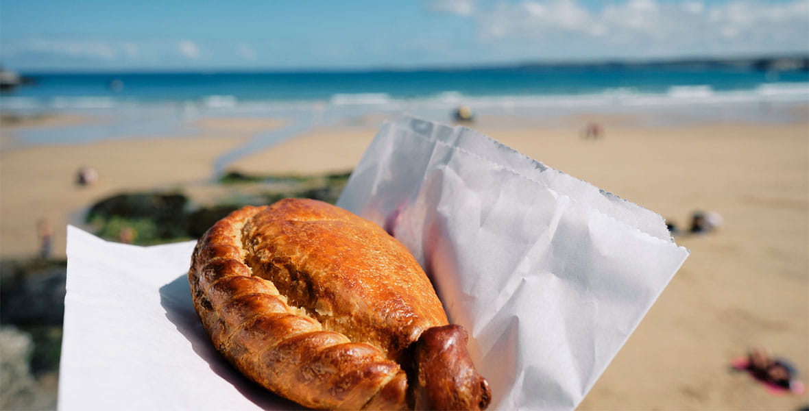 A Cornish pasty with the beach visibile in the background
