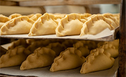 A row of Cornish pasties on a baking tray ready to go in the oven