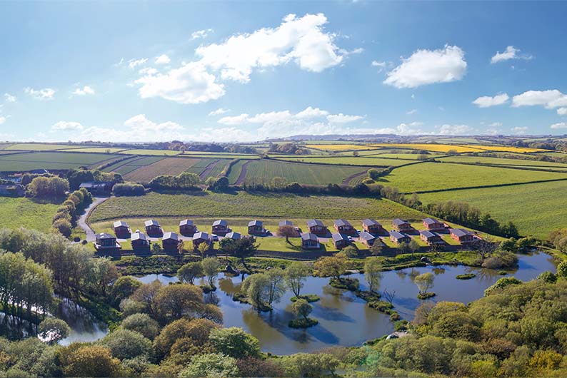Luxury lodges surrounding a lake at White Acres in Cornwall