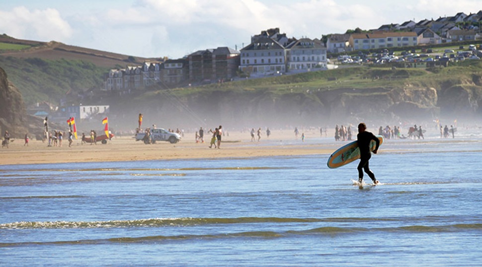 Surfer carrying surf board back to beach at Perranporth