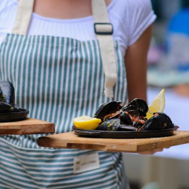 Waitress holding a wooden board of mussels with lemon