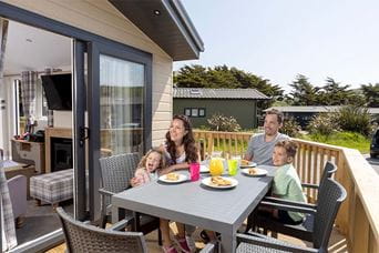 A family dining al fresco on the veranda of their lodge at Ruda Holiday Park in Devon