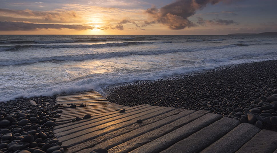 Wooden path on the beach at Westward Ho at sunset
