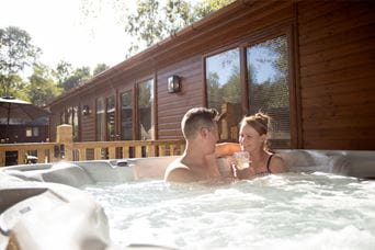 A couple relaxing in a hot tub outside their lodge