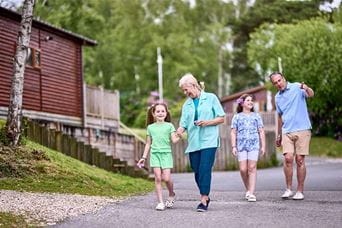 Grandparents and grandkids walking past their holiday lodge at Warmwell Holiday Park in Dorset
