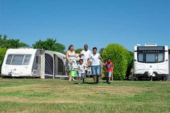 A family walking past a row of touring caravans on a Parkdean campsite in Dorset