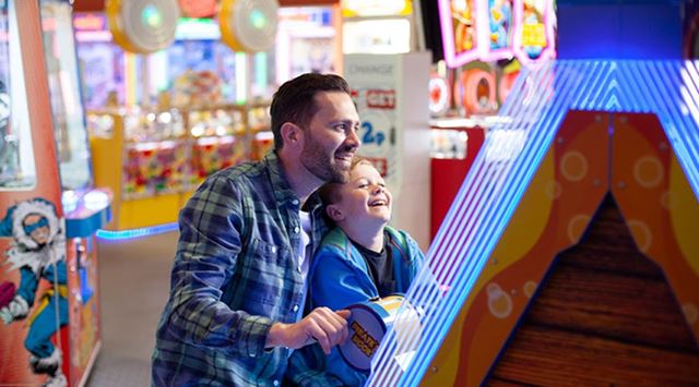 man and small child play a game at the indoor games arcade
