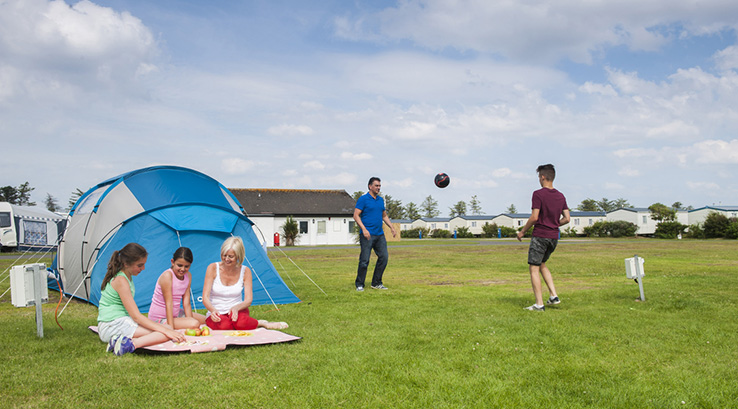 family relaxing at the campsite on nice bright day