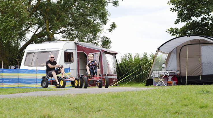 man and child riding pedal scooters at the campsite