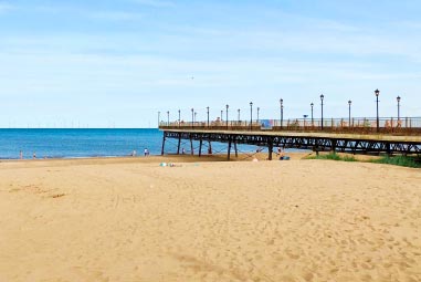 Pier with golden sands and blue sky