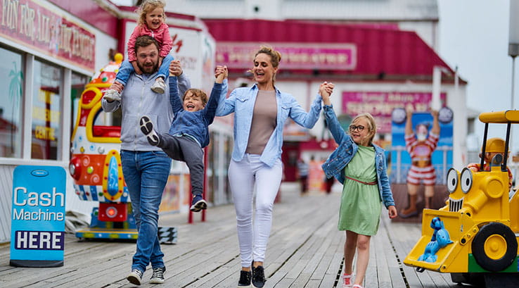family walking along seaside amusement attractions