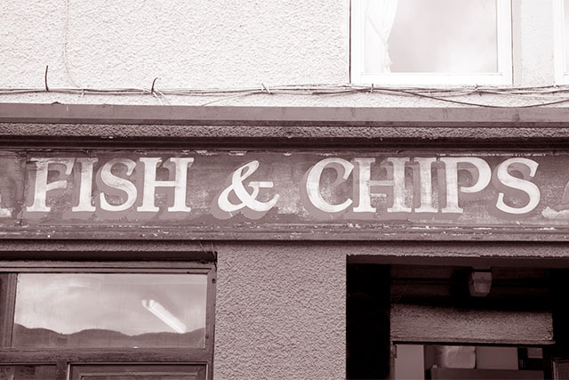 An old black and white photo of a fish and chips shop sign