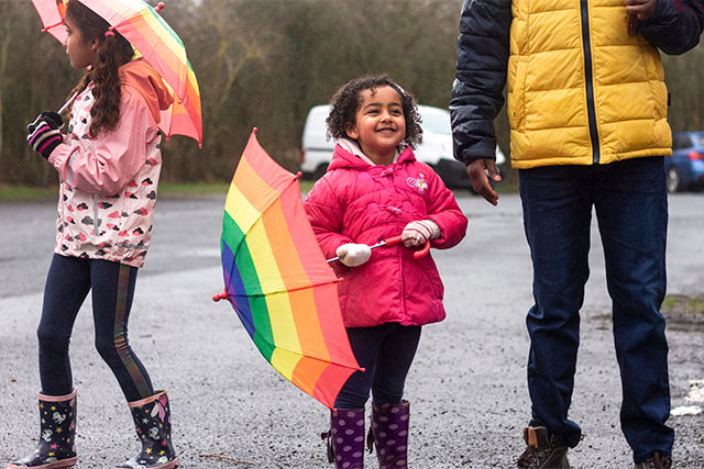 A family holding colourful umbrellas in the rain