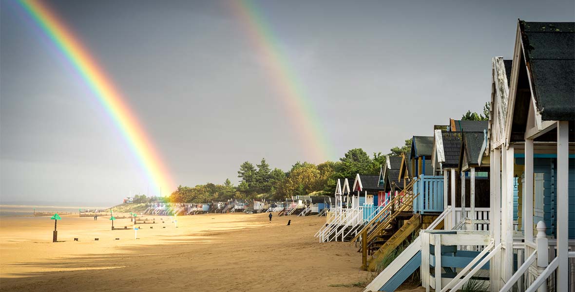 A rainbow appearing over a beach in Norfolk on a rainy day