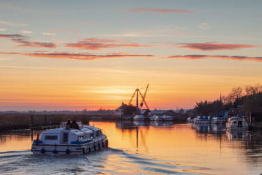 a pleasure boat sailing along a river towards a lighthouse
