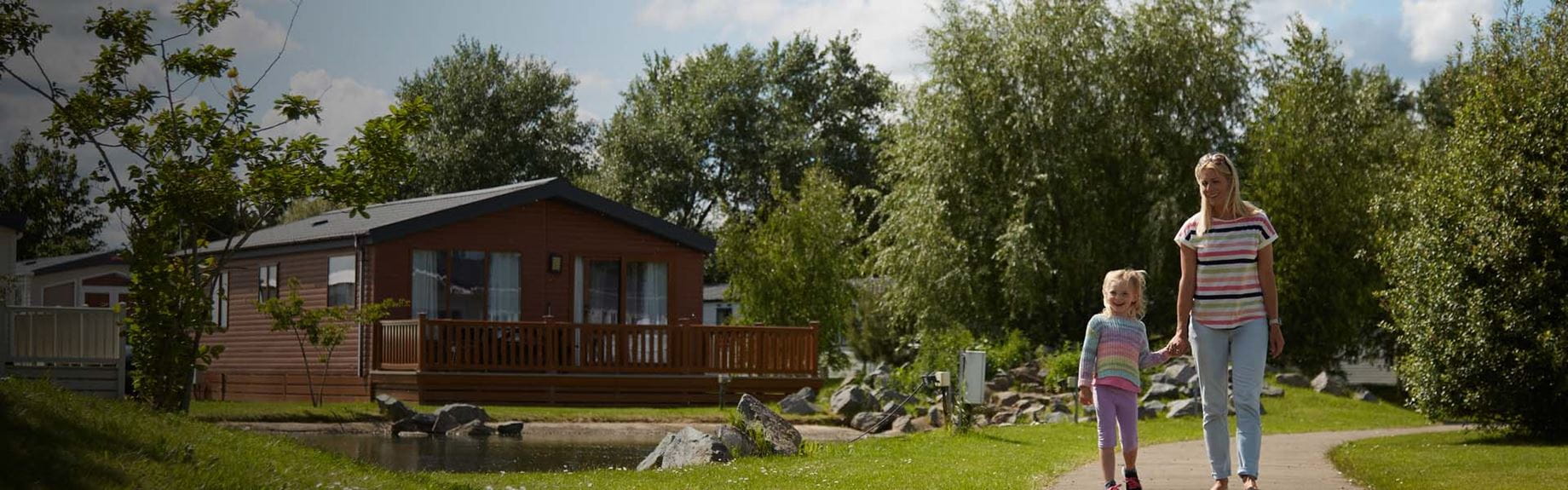 A family walking past a holiday lodge nestled amongst the trees