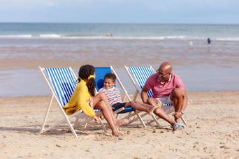 A family sat on deck chairs on a beach near Great Yarmouth