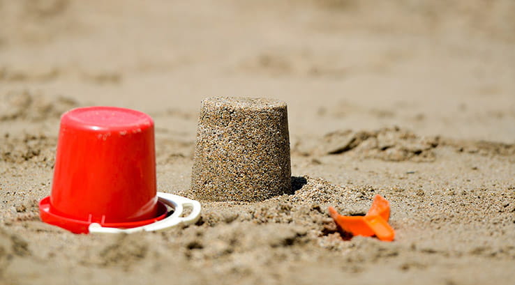 sand castle and red bucket on the beach