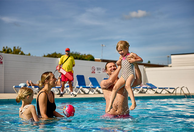 A family enjoying the outdoor swimming pool at Breydon Water Holiday Park in Norfolk