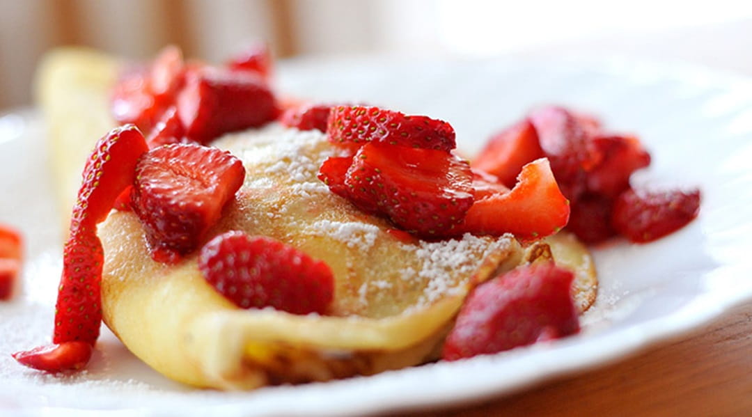 a plate of strawberries and crepes