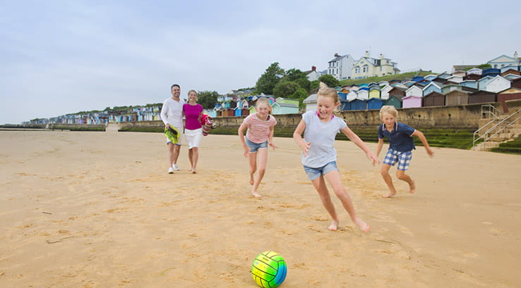 family playing ball games on a beach 