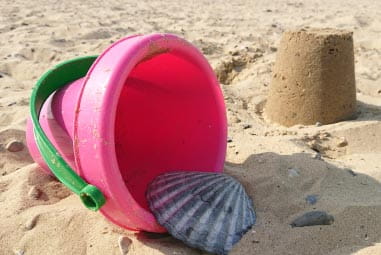 Pink bucket with shell on the beach