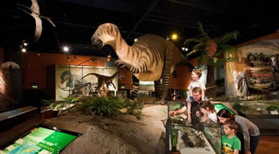 A family studying a dinosaur exhibit at Dinosaur Isle