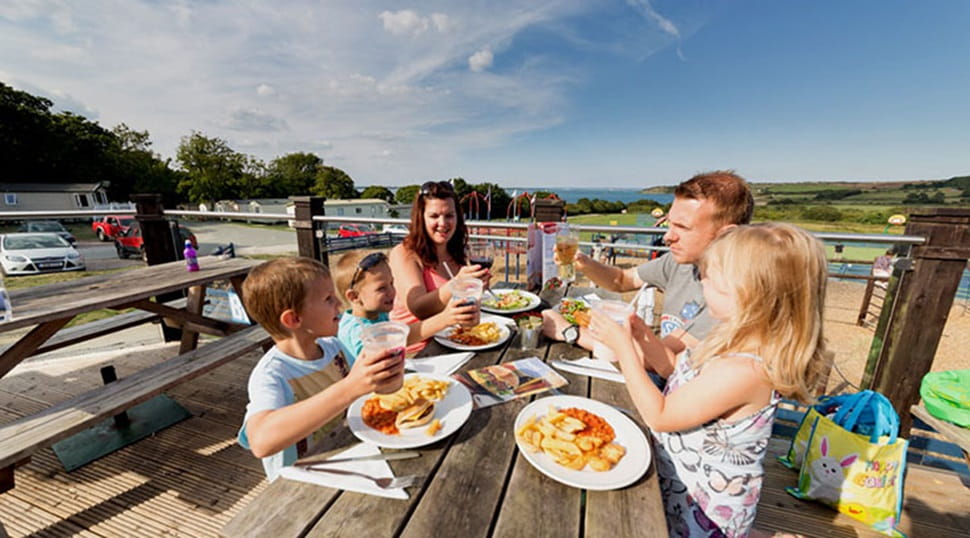 A family enjoying a meal on the outdoor terrace in the sun