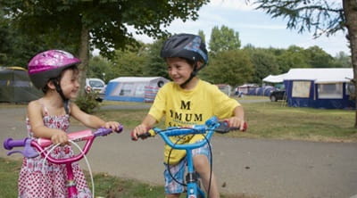 Two children riding bikes on the campsite