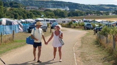 A couple walking through the campsite holding hands 