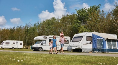 A family walking past caravans and motorhomes in the sun