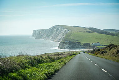 A coastal road on the Isle of Wight with the famous white cliffs visibile in the distance