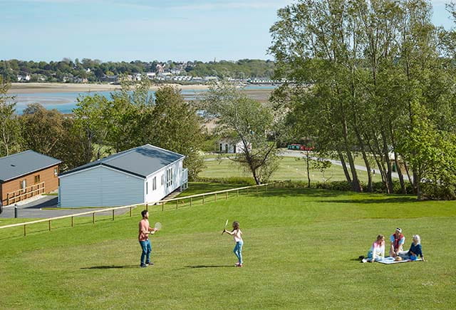 A family having a picnic and playing games on the grass at a Parkdean Resorts holiday park on the Isle of Wight