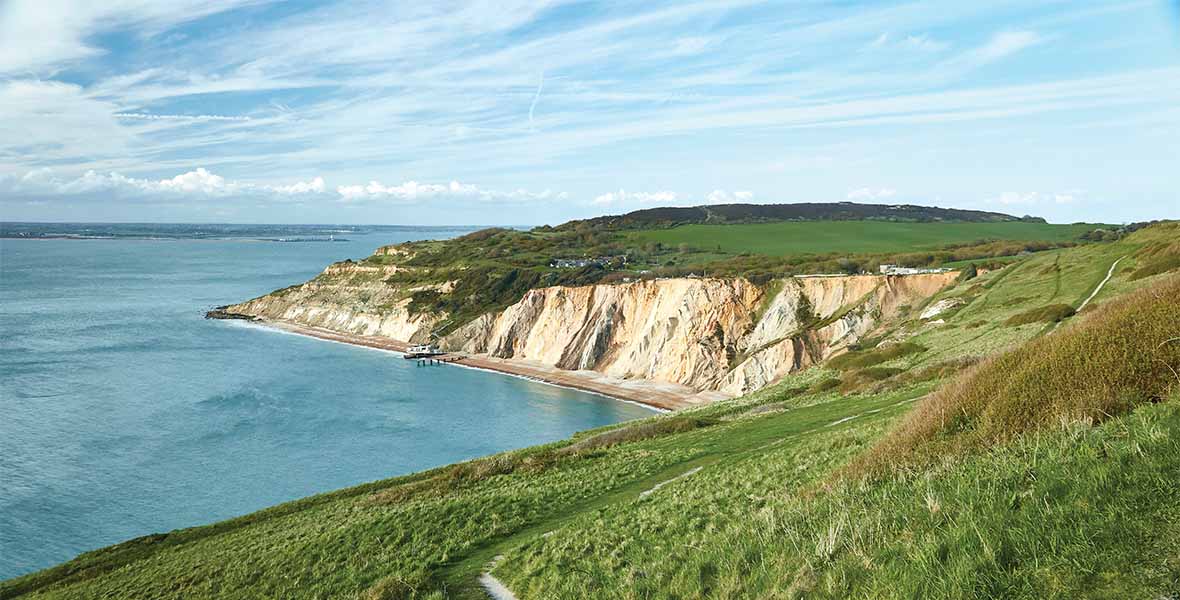 A view over the grassy coastline and white cliffs of the Isle of Wight on a summer day