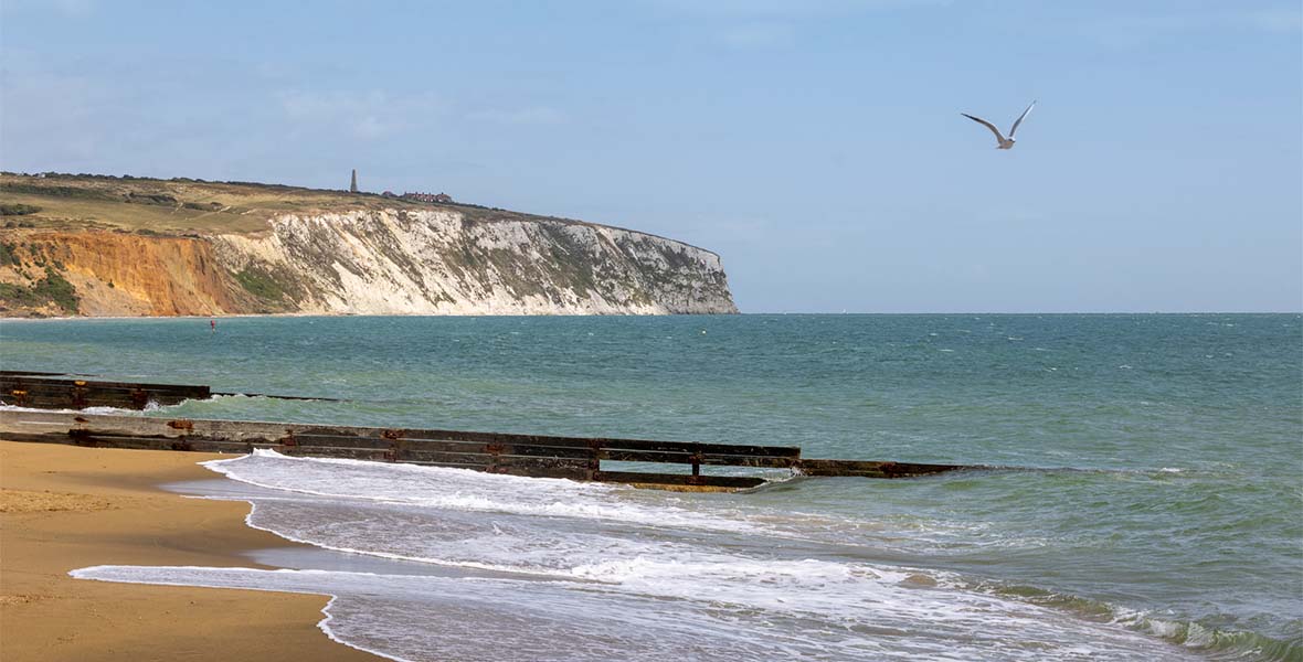 A view along a beach with cliffs in the distance on the Isle of Wight
