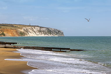A view along a beach with cliffs in the distance on the Isle of Wight
