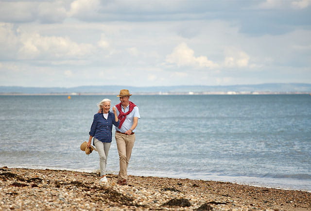 A couple walking along the beach on the Isle of Wight with views over the Solent in the background