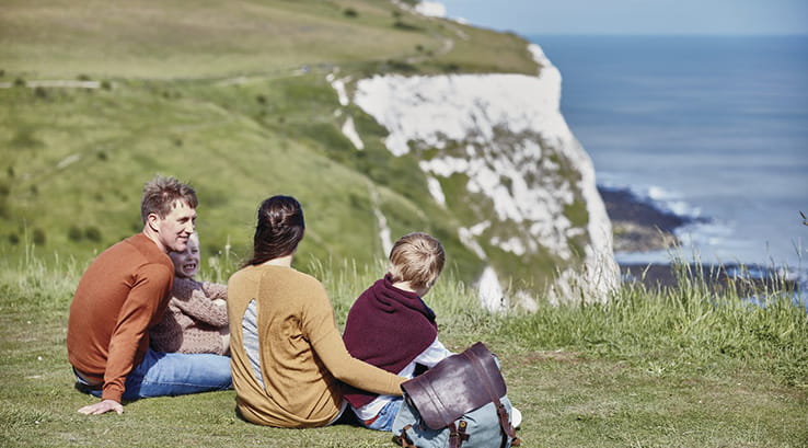 A family relaxing on the grass overlooking the White Cliffs of Dover