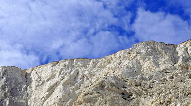 The white cliff face of the White Cliffs of Dover contrasting against the blue sky on the Kent Coast