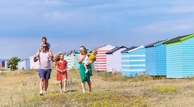 A family walking past colourful beach huts