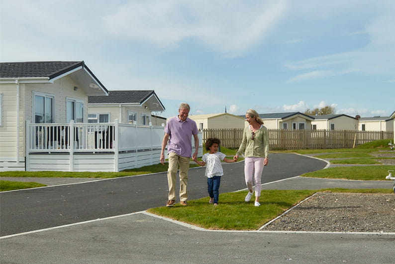 Grandparents and their grandkid walking past their holiday lodge