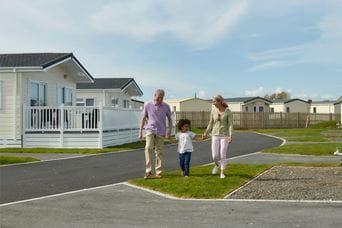 Grandparents and their grandkid walking past their holiday lodge