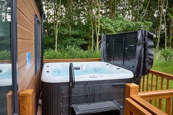 A hot tub on a lodge veranda in a woodland setting