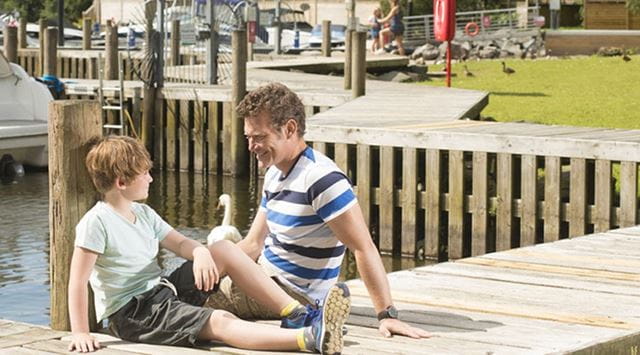 A father and son sitting on the jetty at a lakeside