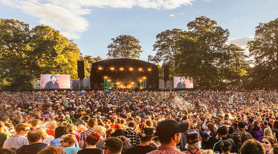 a large crowd in front of a large stage at an outdoor music festival