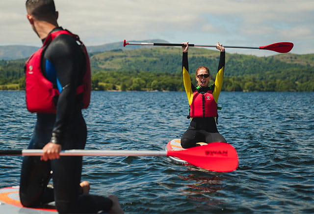 Friends paddleboarding on Lake Windermere in the summer