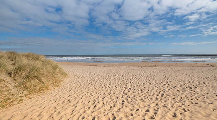 Blue skies over the sandy Cresswell Towers Beach in Northumberland