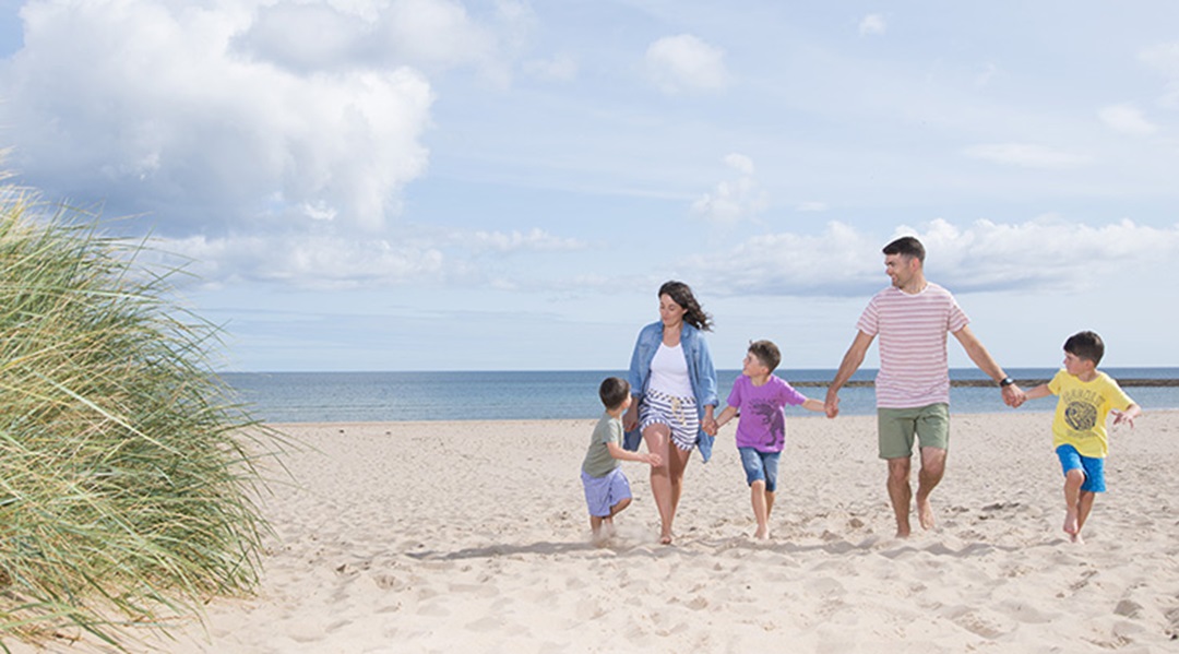 A family walking along the beach holding hands