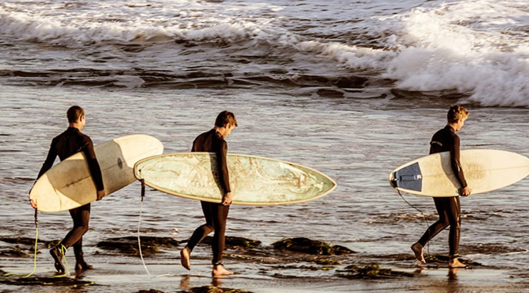 Surfers walking into the sea with surfboards