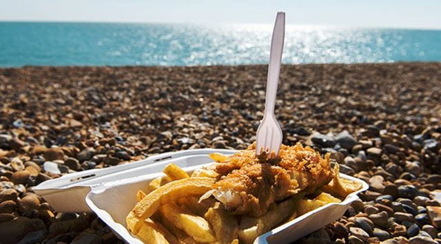 Fish and chips in a tray on a pebble beach